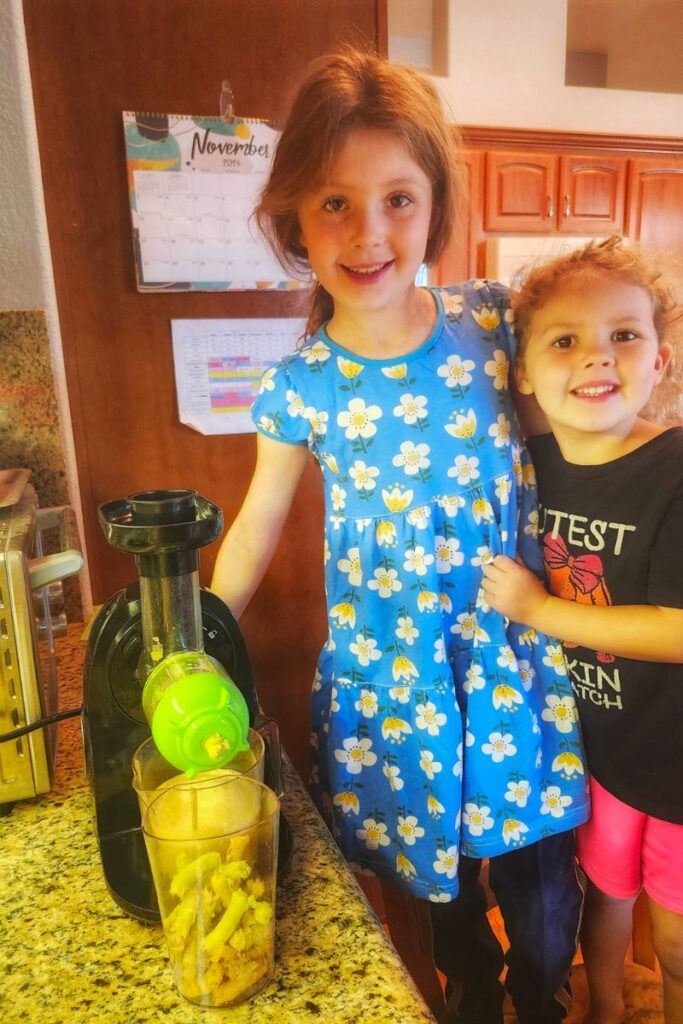 two girls making apple cider with a juicer 