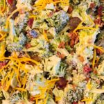 Broccoli salad with bacon, cheddar cheese, cranberries, red grapes and dressing for a pot luck